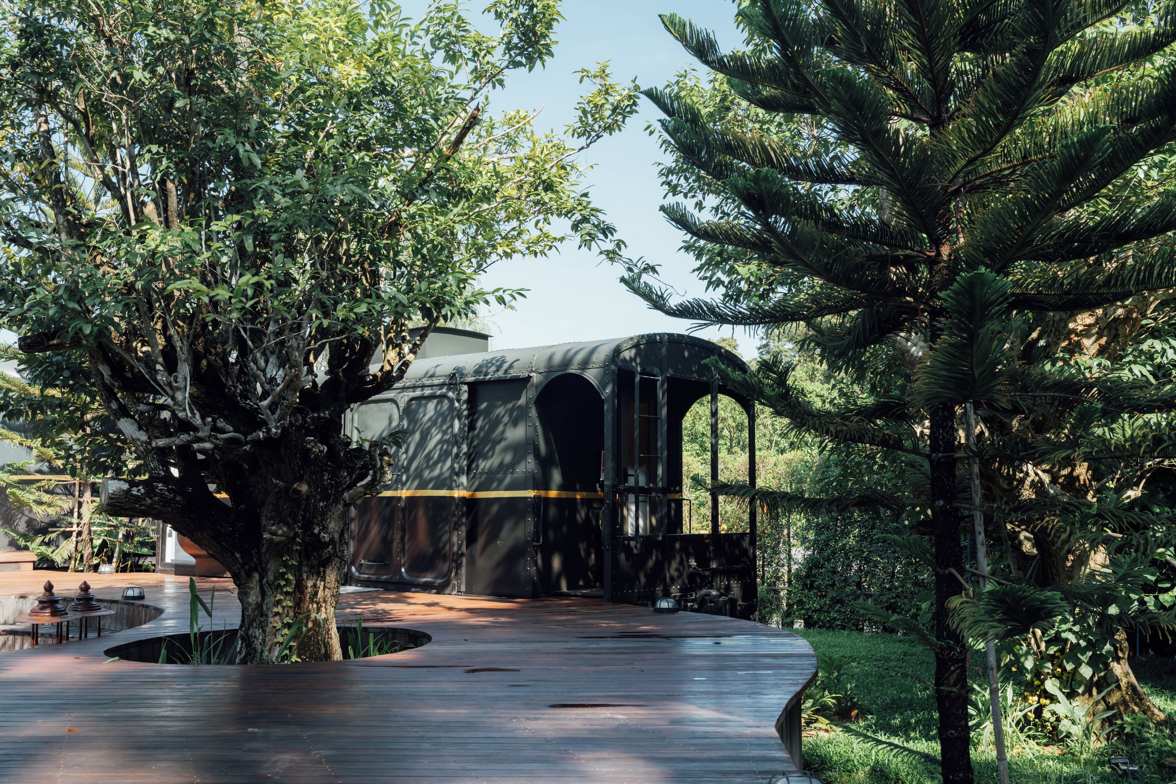 A train station with a covered waiting area surrounded by lush greenery.