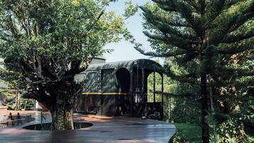 A train station with a covered waiting area surrounded by lush greenery.