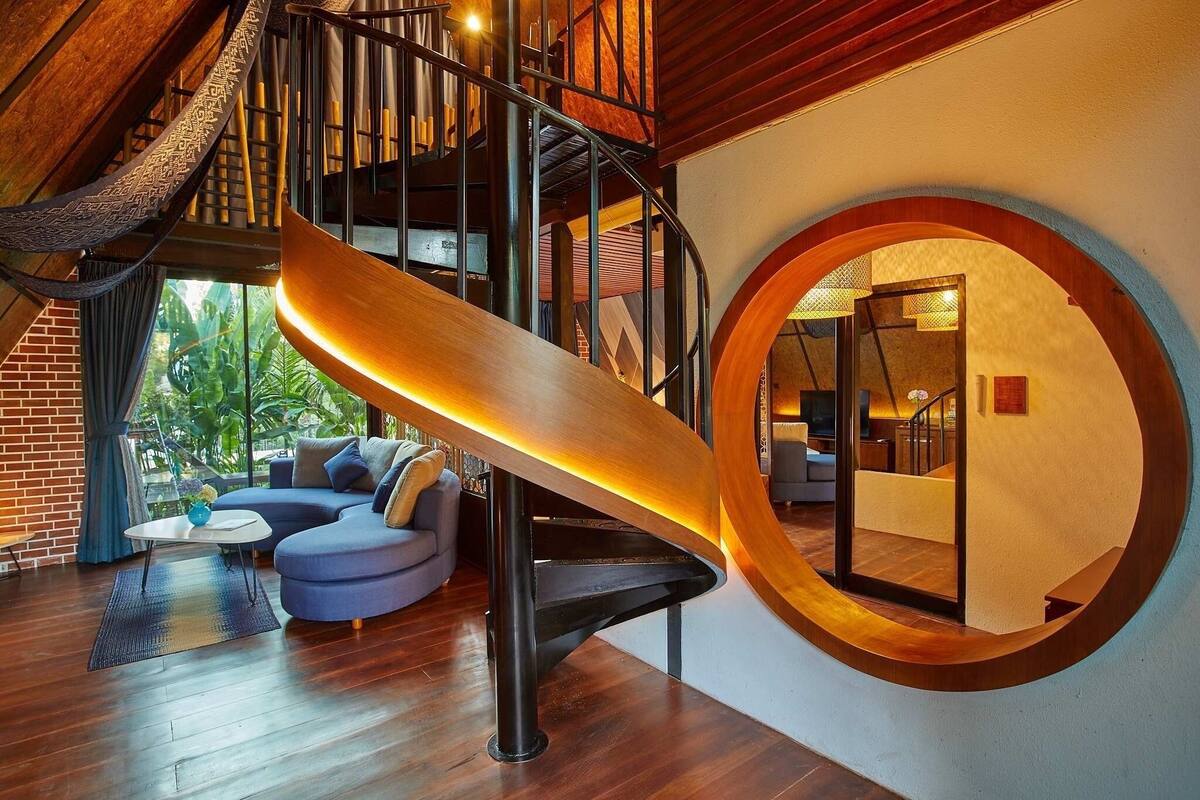 Un interior moderno con una escalera de caracol, un detalle de madera circular y un sofá azul.