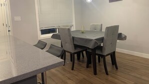 A dining area with a table, chairs, a chandelier, and a window with blinds.