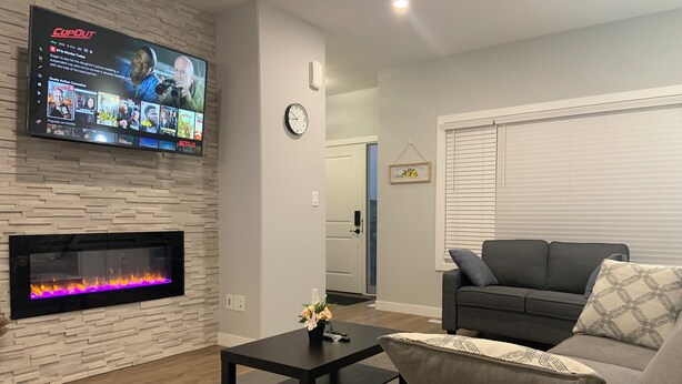 A living room with a flat-screen TV mounted on a stone wall, a fireplace, a sofa, and a coffee table.
