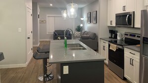 A modern kitchen with white cabinets, stainless steel appliances, and a central island with a sink.