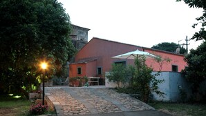 A building with a red facade, a stone pathway leading to the entrance, and a large umbrella providing shade. - Lumia (Riposto)
