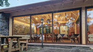 A restaurant with outdoor seating, stone walls, and wooden tables. - Lumia (Riposto)