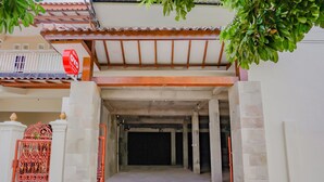 A building entrance with a covered walkway, a decorative gate, and a balcony with a railing. - Hotel O Kenari House Syariah (Depok)
