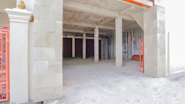 An interior space with exposed concrete pillars, a tiled floor, and a partially constructed ceiling. - Hotel O Kenari House Syariah (Depok)