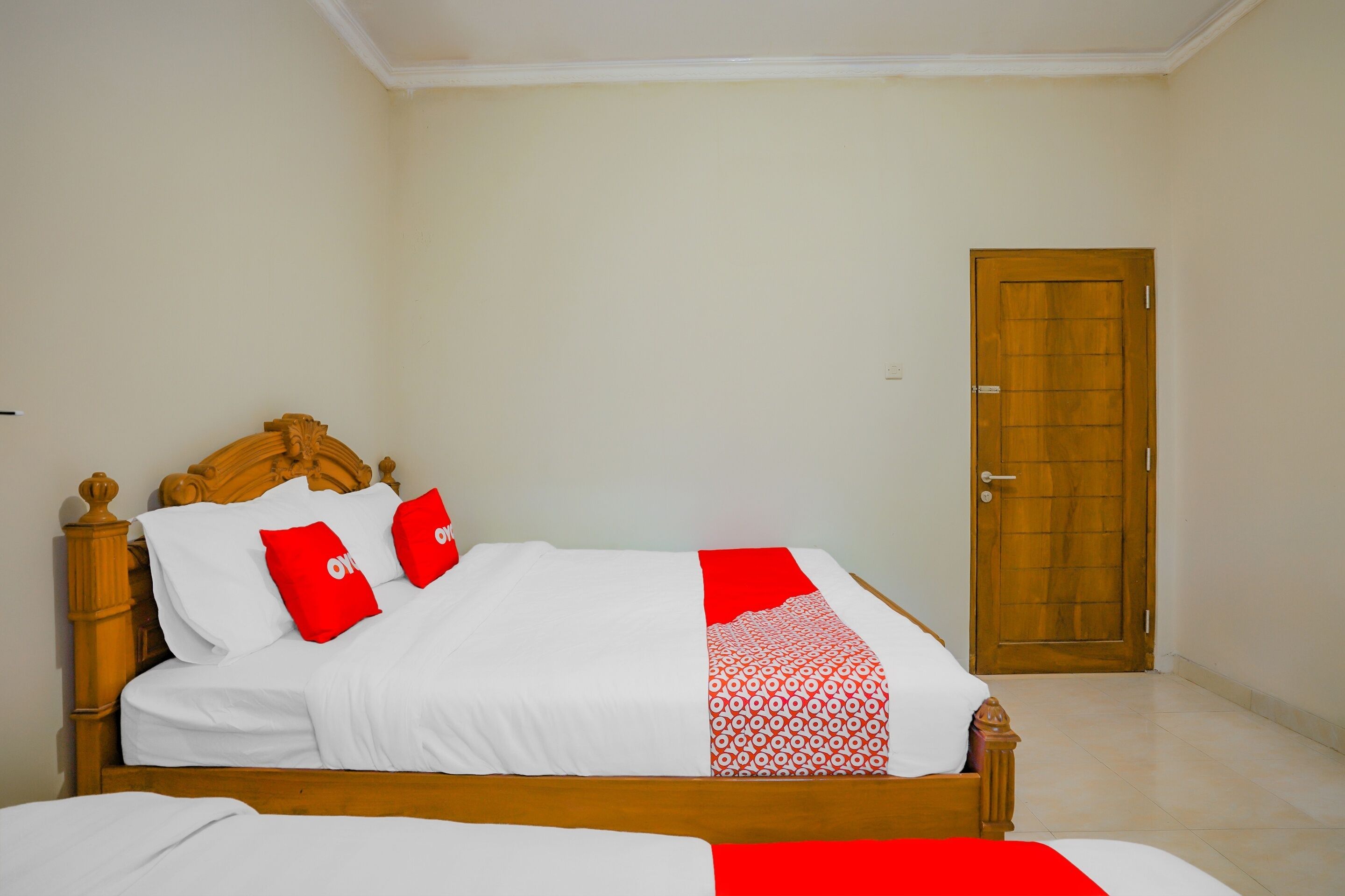 Un lit bien fait avec une tête de lit en bois, une porte en bois et un mur sobre.
