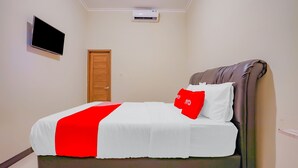 A neatly made bed with a red and white bedspread, a brown headboard, and a red pillow. - Hotel O Kenari House Syariah (Depok)