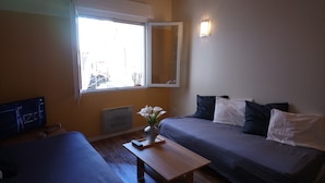 Ein Schlafzimmer mit zwei Betten, einem Fenster, einem Heizkörper und einem Fernseher.