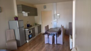 Eine Küche mit Kühlschrank, Backofen und Mikrowelle. Ein Esstisch mit Stühlen steht bereit.