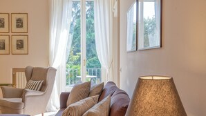 Et godt oplyst rum med sofa, lænestol og et bord med lampe.