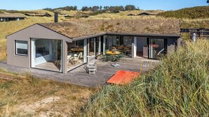 A modern house with a glass-enclosed patio area, a deck, and a view of the surrounding landscape. - "Hoat" - 300m from the sea by Interhome (Saltum)
