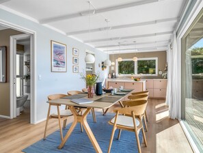 A modern kitchen with a large window, a dining area with a table and chairs, and a hallway leading to a bathroom. - "Hoat" - 300m from the sea by Interhome (Saltum)