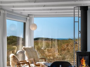 A room with a large window, a fireplace, and a view of the outdoors. - "Hoat" - 300m from the sea by Interhome (Saltum)