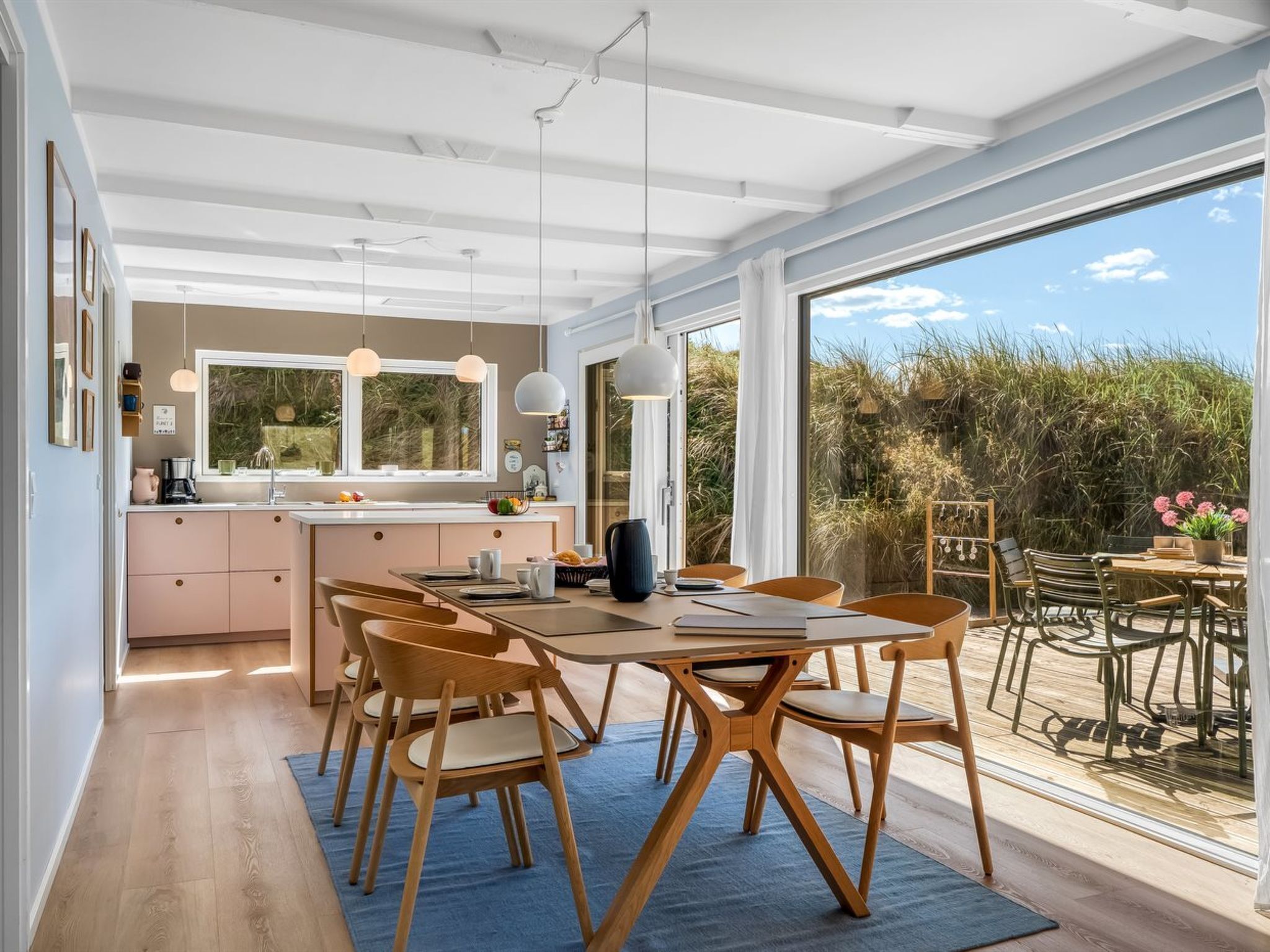 A modern kitchen with a dining area, large windows, and a view of the outdoors.