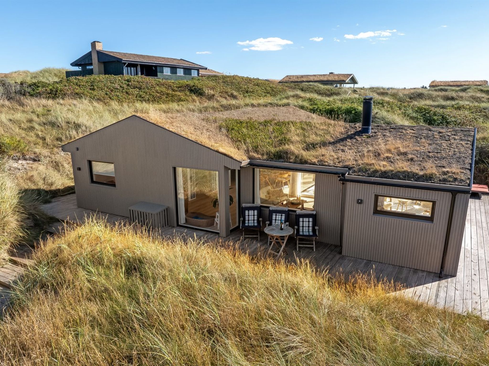 A modern house with a large open patio, a dining area, and a view of the surrounding landscape.