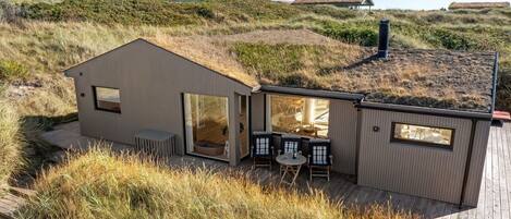 A modern house with a large open patio, a dining area, and a view of the surrounding landscape.