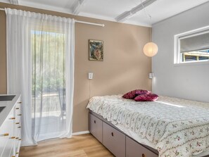 A bedroom with a bed, a window, a painting, and a ceiling light.