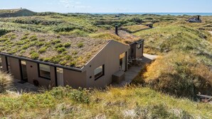 A modern house with a flat roof, large windows, and a wooden deck. - "Hoat" - 300m from the sea by Interhome (Saltum)