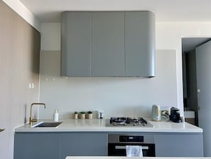 A modern kitchen with grey cabinets, a stainless steel sink, and a gas stove.