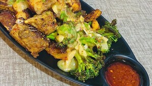 En tallerken mad med kartofler, broccoli og rød sauce.