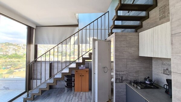 A modern kitchen with a built-in stove, a coffee machine, and a view of the city.