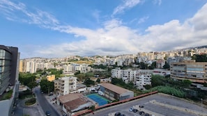 A cityscape with residential buildings, a tennis court, and a parking area.