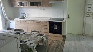 Cocina compacta con armarios de madera, horno integrado y lavavajillas.
