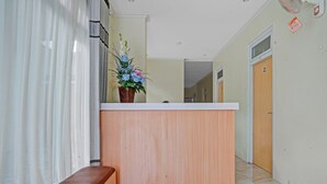 Un espace d’accueil avec un comptoir en bois, un banc et un arrangement floral.