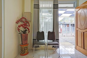 A room with two chairs, a potted plant, and a wooden cabinet. - OYO 90804 Oma Uti Homestay Syariah (Yogyakarta)