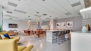 A modern hotel lobby with a central bar area, seating arrangements, and a large screen displaying a cityscape. - 3BR Penthouse with European Flair & Amazing Views (Miami)