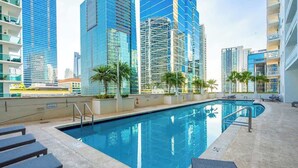 A swimming pool with lounge chairs, surrounded by high-rise buildings. - 3BR Penthouse with European Flair & Amazing Views (Miami)