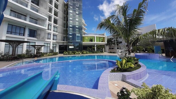 Un hotel con piscina, zona de estar al aire libre y un edificio moderno con balcones.