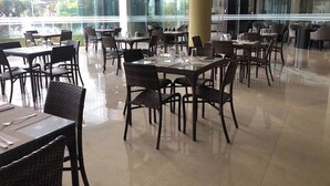 Un comedor interior espacioso con varias mesas y sillas, ventanas amplias que ofrecen vistas al exterior y un diseño arquitectónico moderno con divisiones de vidrio.