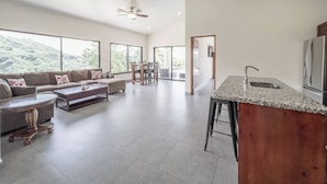 A spacious living area with a sofa set, a dining table, and a kitchen island with a sink. - Journeys End-stunning Views In Gated Community (Atenas)