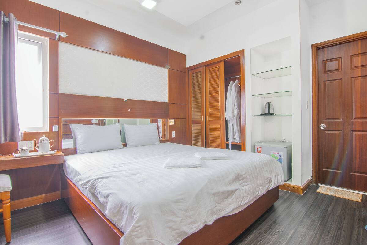 Une chambre d’hôtel avec un grand lit, une armoire en bois et un bureau équipé d’une bouilloire.