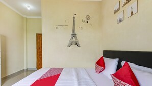 Een hotelkamer met een bed, een muur met Parijse decoratie en een deur.