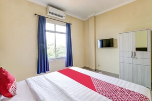 A hotel room with a bed, a wardrobe, a TV mounted on the wall, and an air conditioning unit. - Hotel O Dangau Datuk Guesthouse (Sleman)