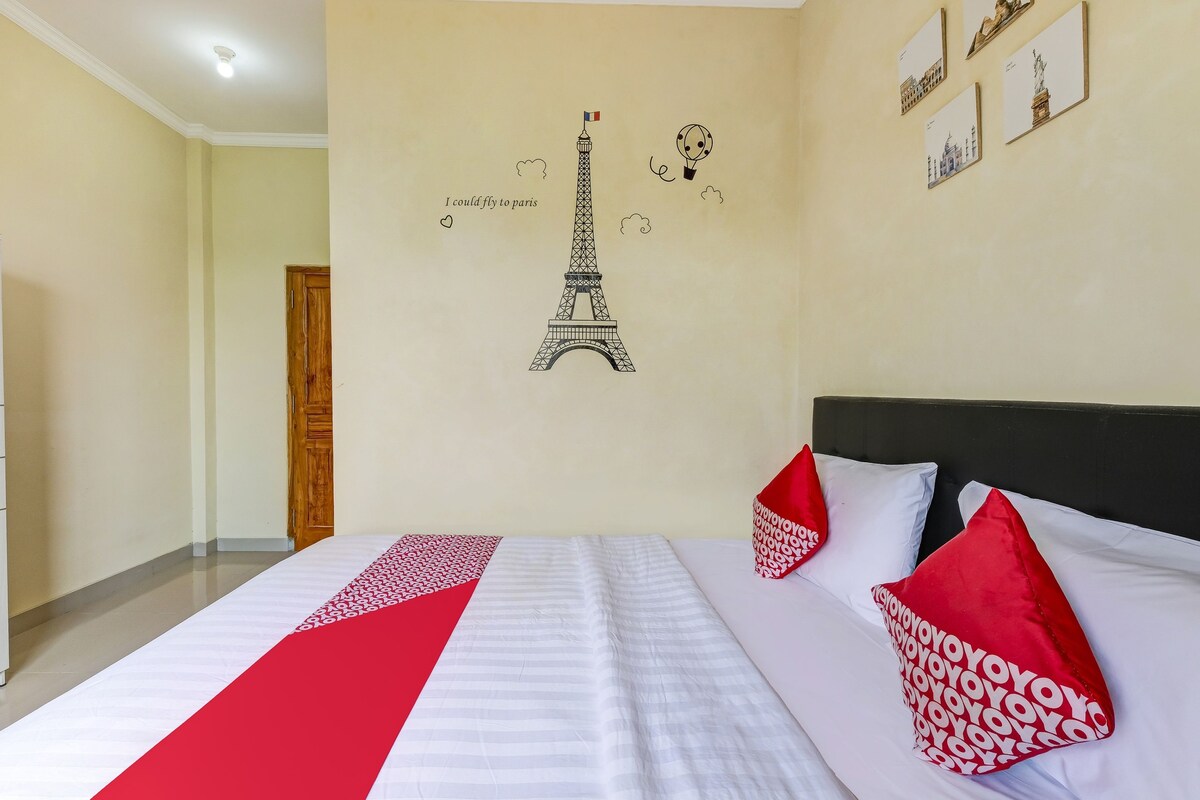 A hotel room with a bed, a wall with a Paris-themed decoration, and a door.