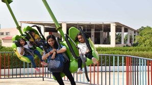 A roller coaster with green seats and a metal fence in the background. - Amazing Fun World By Nexottel (Dwarka)