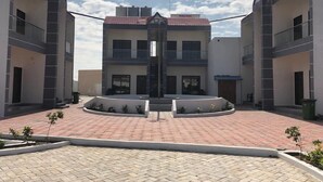 A courtyard with a central fountain, surrounded by buildings with balconies and a tiled roof. - Amazing Fun World By Nexottel (Dwarka)