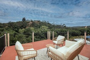A balcony with wicker furniture and a view of a forested hillside. - Sunset Views Retreat (Vista)