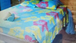 Una cama con una colcha estampada de flores coloridas y un dosel azul.