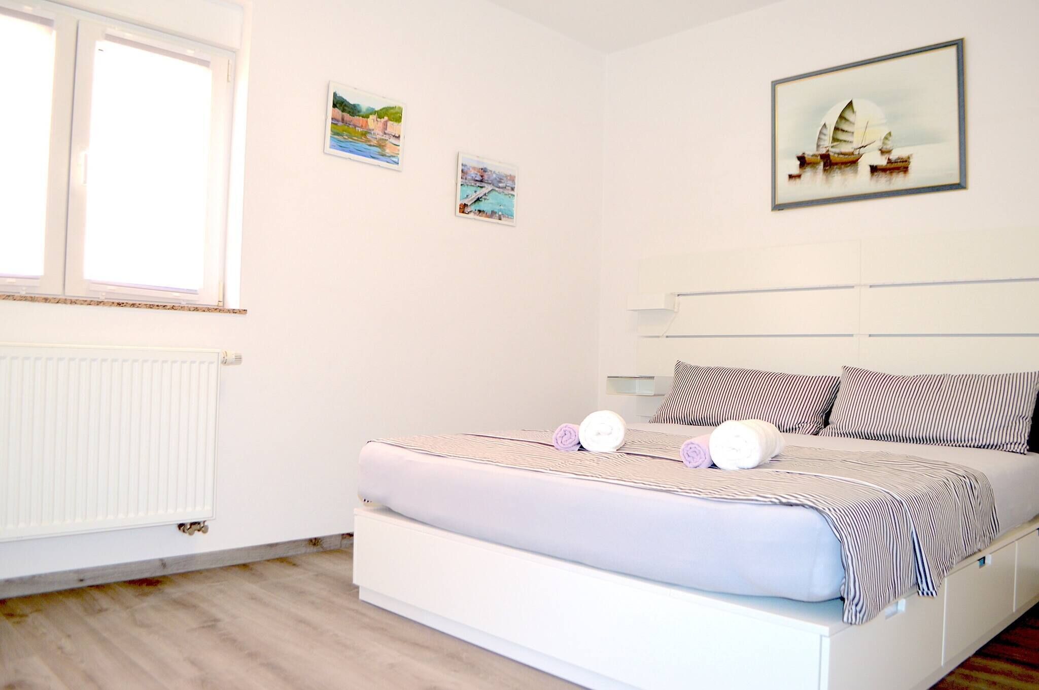A bedroom with a bed, a window, and two wall-mounted pictures.
