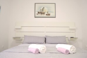 Habitación de hotel con una cama, dos almohadas, cabecero, un cuadro colgado en la pared y dos toallas enrolladas.