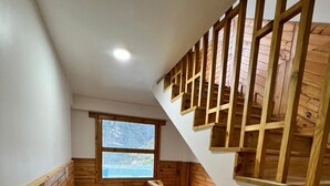 A wooden staircase with a view of a mountain through a window. - Hotel Camp De Base (Namche Bazar)