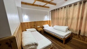 A room with two wooden beds, a small wooden table, and a ceiling with exposed beams. - Hotel Camp De Base (Namche Bazar)