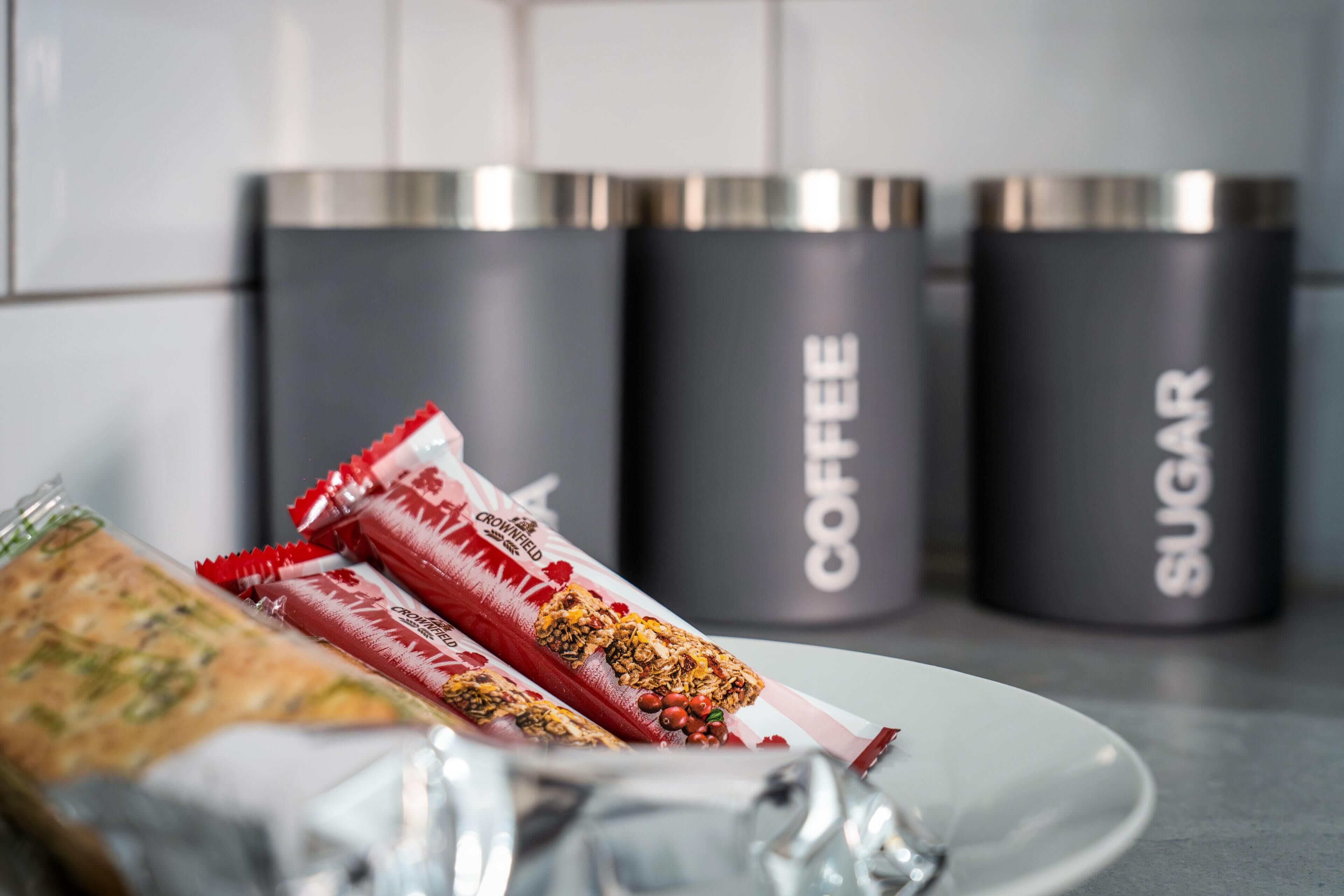 En tallerken med færdigpakket mad samt to beholdere mærket "COFFEE" og "SUGAR".