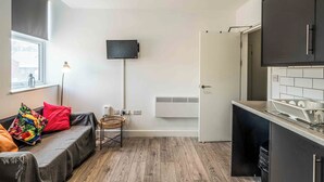 A modern kitchen with a built-in stove, a dining area with a table and chairs, and a cozy seating area with a sofa and cushions. - 1 bed Apartment near Liverpool Lime street (Old Swan)