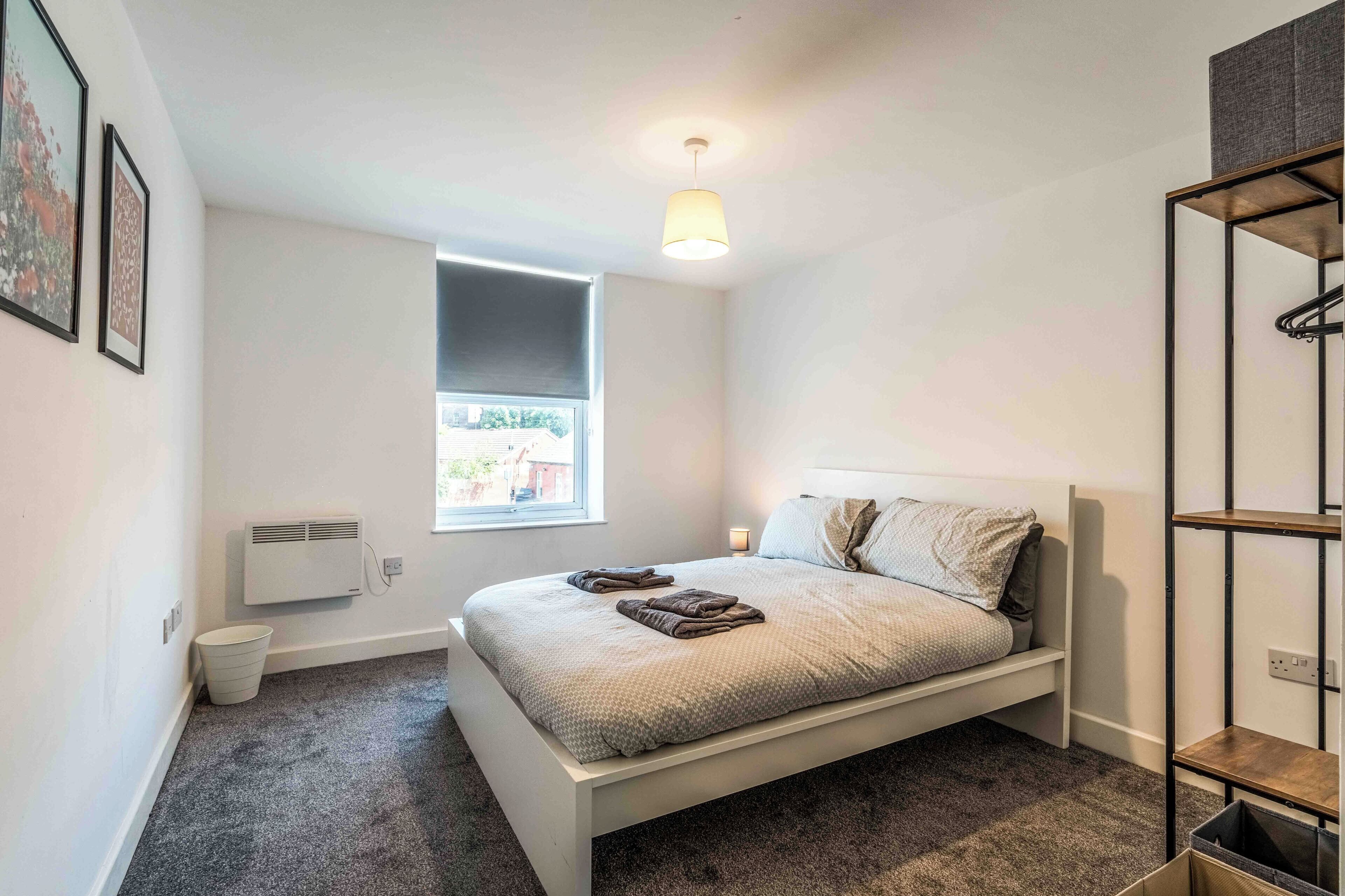 Ein kleines, modernes Schlafzimmer mit einem Einzelbett, einem Fenster, einer Heizung und einer Hängeleuchte.